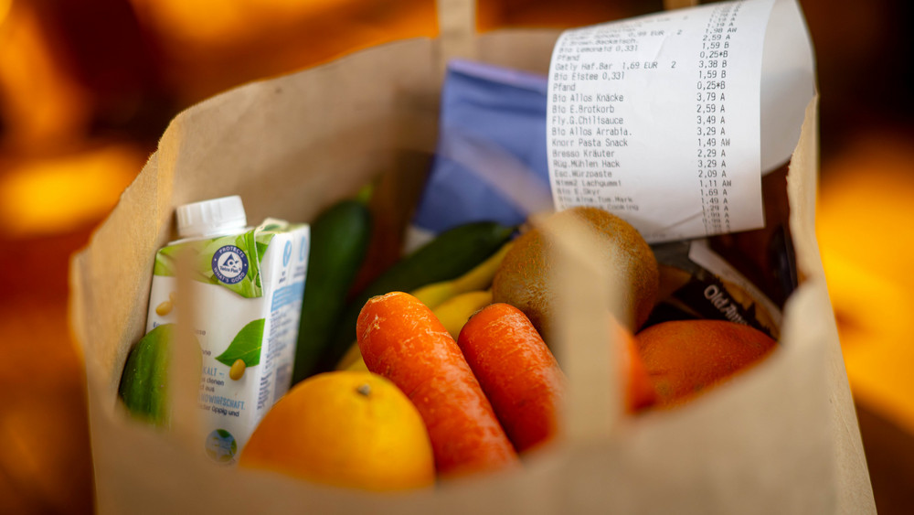 Ein Kassenbon liegt auf den Lebensmitteln in einer Einkaufstüte. Die Inflation in Deutschland geht weiter zurück (Symbolbild).
