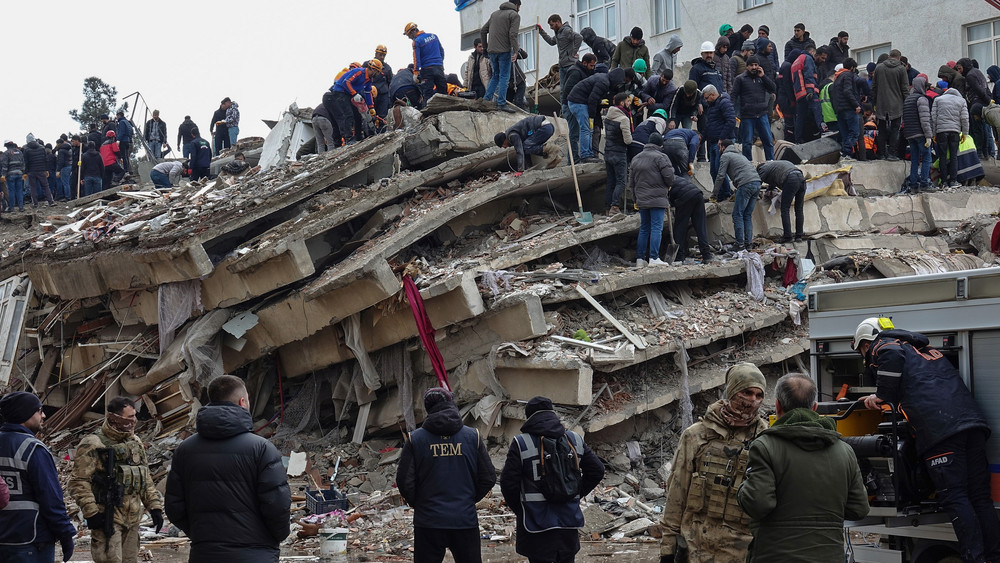 Such- und Rettungsteams sind in den Trümmern eines Gebäudes im Einsatz.