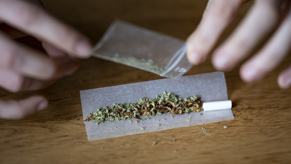 Tüte mit Cannabis, jemand dreht sich einen Joint