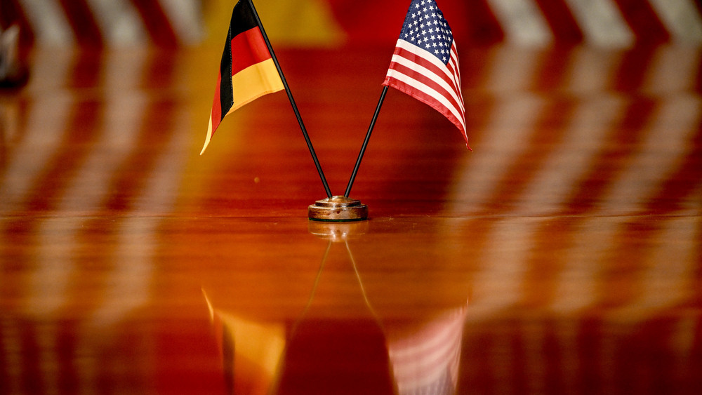Die deutsche und die US-amerikanische Flagge stehen auf einem Tisch.