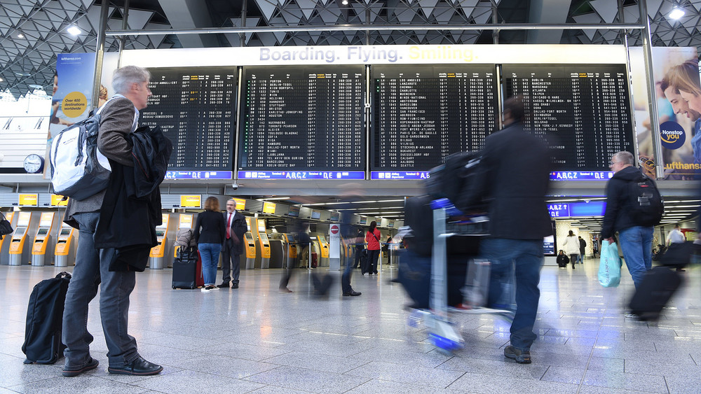 Abflugtafel und Passagiere am Frankfurter Flughafen