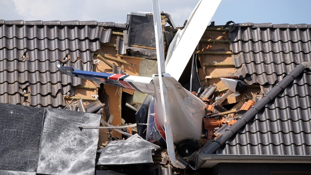 Das abgestürzte Leichtflugzeug steckt im Dach eines Hauses.