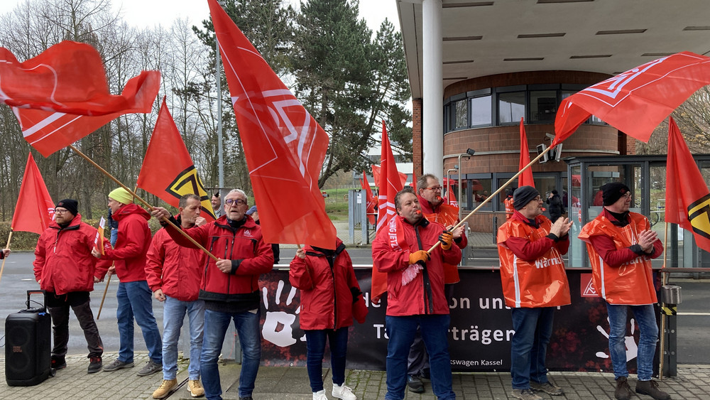 Beschäftigte des Volkswagen-Werks Kassel im nordhessischen Baunatal nehmen an einer befristeten Arbeitsniederlegung teil und schwenken Fahnen der IG Metall.
