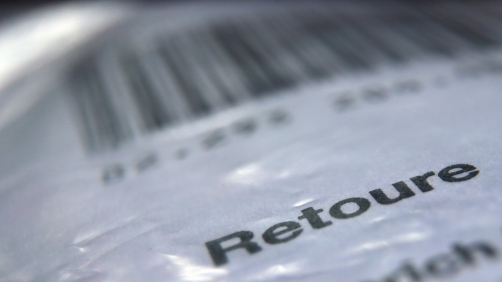 Das Wort «Retoure» steht auf dem Retourenaufkleber eines in Folie verpackten Päckchens, welches an einen Online-Versandhändler zurück geschickt werden soll. 