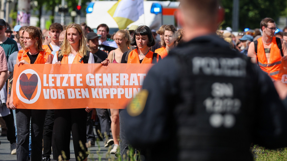 Teilnehmer eines Protestmarsches der Letzten Generation gehen um den Leipziger Ring. 