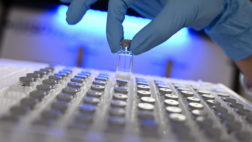 Eine Biologie-Laborantin entnimmt in einem Labor des Darmstädter Pharma- und Technologiekonzerns Merck KGaA eine gefriergetrocknete Probe aus einem Behälter.