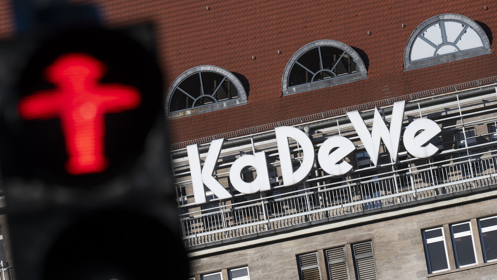 KaDeWe-Logo im Hintergrund, vorne ein rotes Ampelmännchen