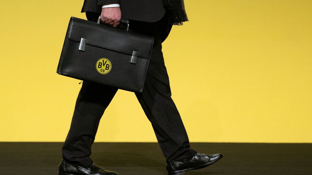 Aufsichtsratsmitglied Bernd Geske kommt bei der Hauptversammlung von Fußball-Bundesligist Borussia Dortmund mit einer Aktentasche mit BVB-Logo auf das Podium.