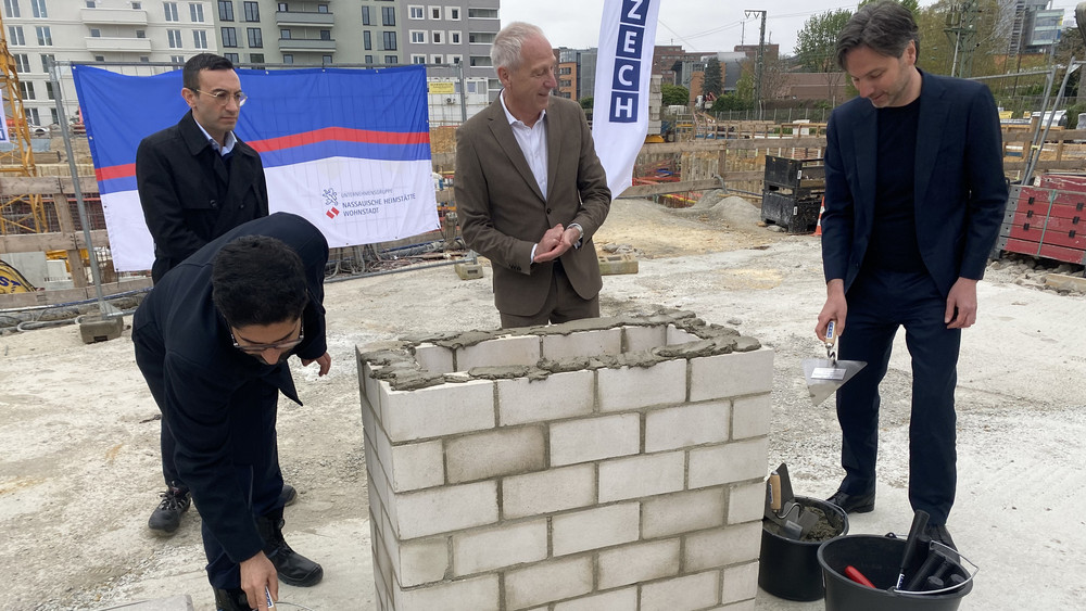 Oberbürgermeister Mike Josef, Hessens Wirtschaftsminister Kaweh Mansoori, Leitender Geschäftsführer der Unternehmensgruppe Nassauische Heimstätte | Wohnstadt Dr. Thomas Hain und Frankfurts Planungsdezernent Professor Marcus Gwechenberger haben gemeinsam den Grundstein für das Bauprojekt gelegt.