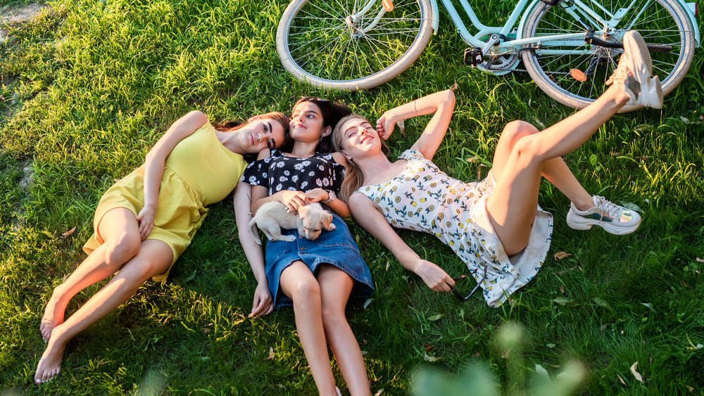Drei Frauen liegen im Sommer auf der Wiese mit ihren Fahrrädern
