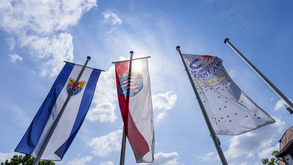 Das Wappen von Pfungstadt (l-r), der Hessen-Löwe und die «Hessentags-Flagge» wehen in der Innenstadt im Wind.