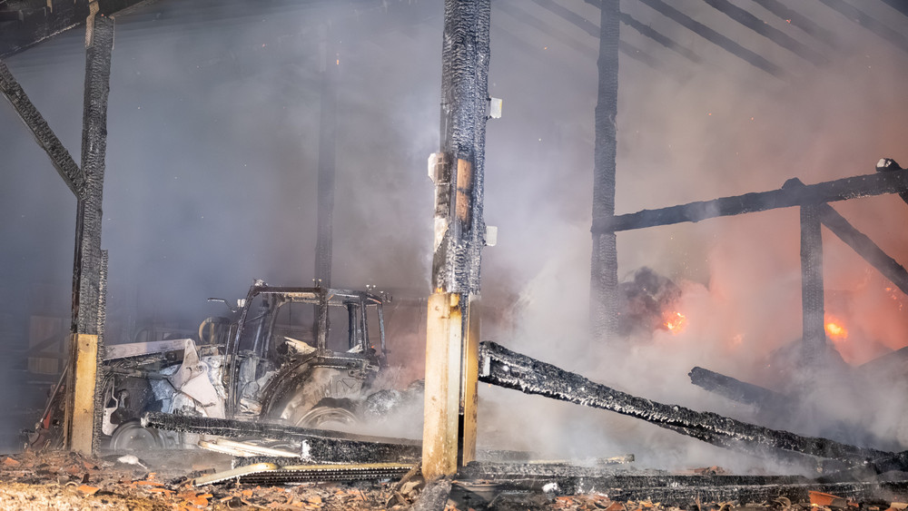 Gerippe der Lagerhalle in Michelstadt, ausgebrannter Traktor und Rauch