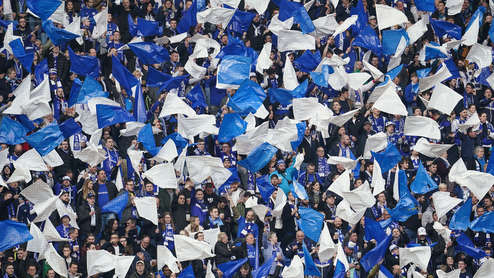 Schalker Fans halten weiße und blaue Fahnen in die Höhe beim Bundesliga-Spiel zwischen und Hoffenheim und Schalke 04 am 9. April 2023. Am Rande dieses Spiels passierte der Vorfall.