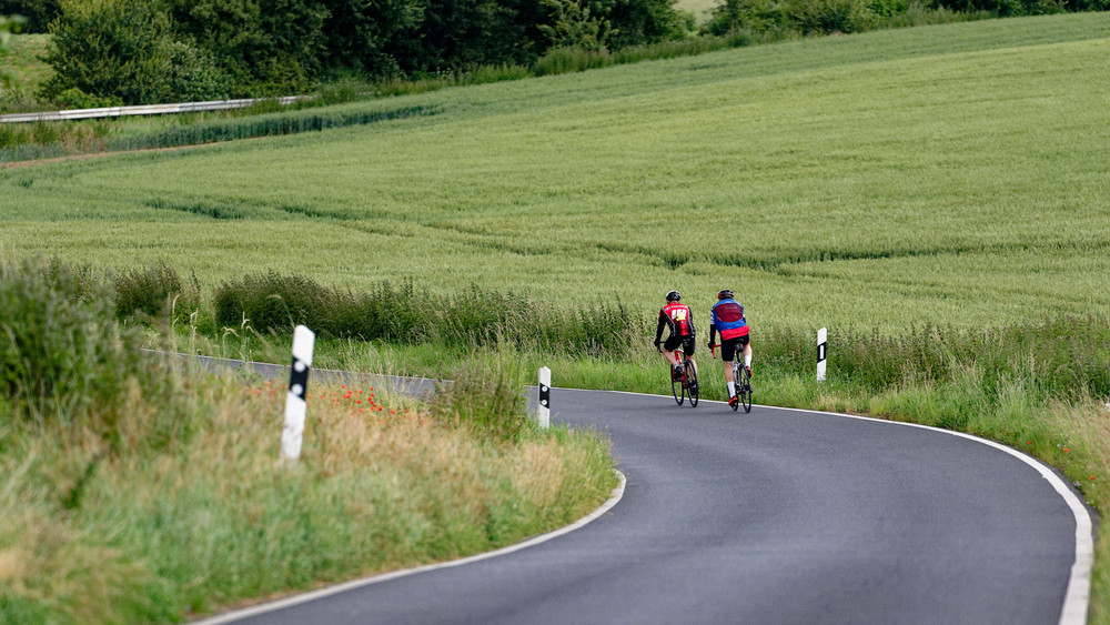 Zwei Radfahrer fahren auf einer Landstraße - ein Radweg fehlt (Symbolbild).