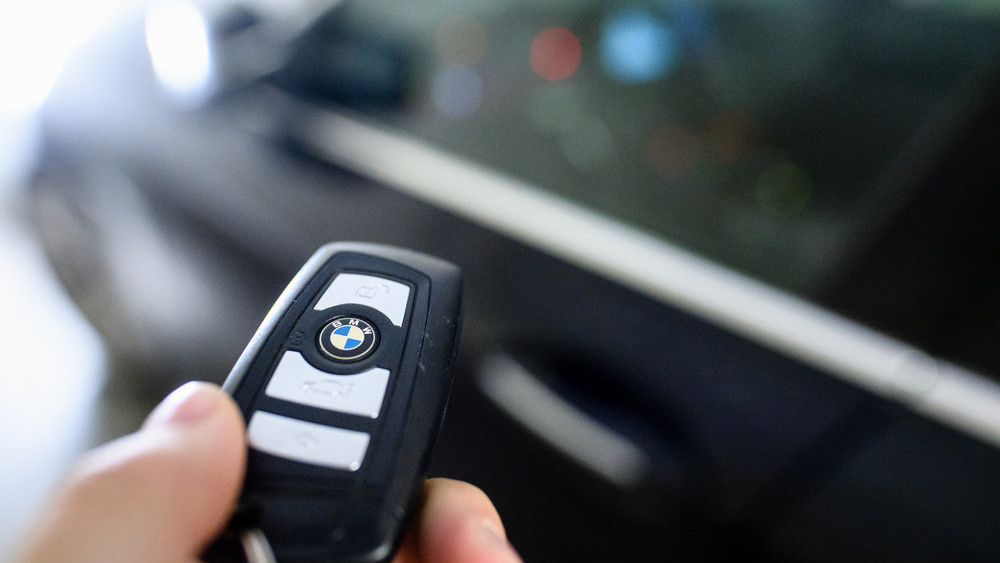Ein Mann hält den Schlüssel eines BMW in der Hand.