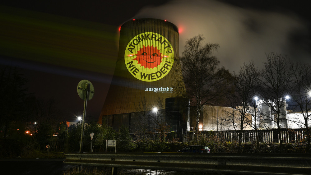 Aktivisten der Anti-Atom-Bewegung projizieren eine große Anti-Atom-Sonne auf den Kühlturm des Atomkraftwerkes Emsland. Anlass ist die Abschaltung der letzten AKW am 15. April. 