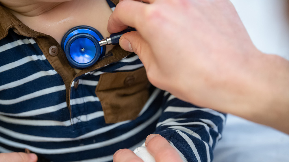 Ein Arzt untersucht ein Kind mit einem Stethoskop