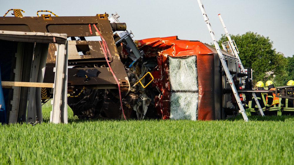 Eine Lok liegt neben den Gleisen auf einem Feld, Feuerwehr und Polizei stehen daneben. Bei einem Unfall mit zwei Güterzügen bei Münster in Südhessen war ein Lokführer ums Leben gekommen.