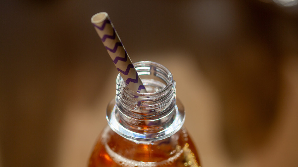 Eine geöffnete Flasche mit einem zuckerhaltigen Erfrischungsgetränk steht auf einem Tisch.