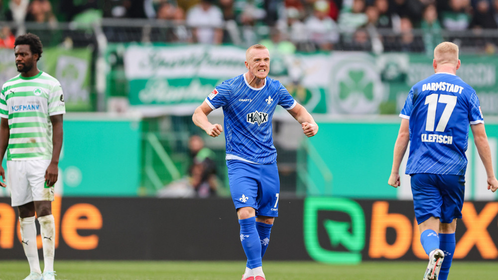  Isac Lidberg (M) und Kai Klefisch vom SV Darmstadt 98 (r) jubeln über Lidbergs Treffer zum 3:0, Gideon Jung (l) von Greuther Fürth schaut betreten.