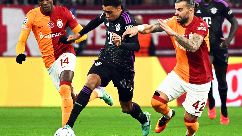 Münchens Jamal Musiala (M) in Aktion gegen Galatasarays Spieler Wilfried Zaha (l) und Abdülkerim Bardakci.