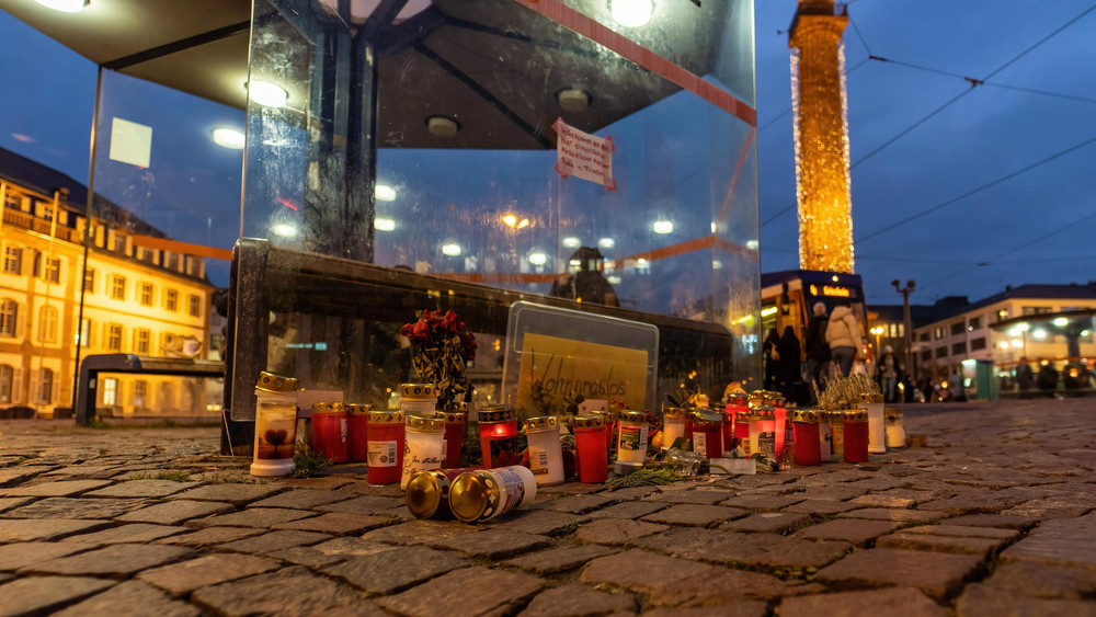 Kerzen und Blumen liegen auf dem Luisenplatz in der Innenstadt Darmstadt an einer Haltestellenüberdachung. Sie erinnern an einen Obdachlosen, der dort wenige Tage zuvor getötet worden war.