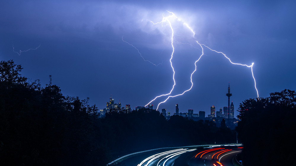 Blitze sind während eines Gewitters über der Skyline von Frankfurt am Main und der Autobahn A661 zu sehen.