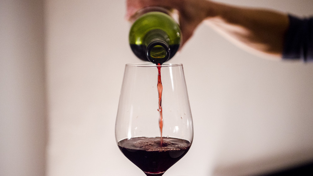 Eine Frau gießt zuhause Wein in ein Glas. Die Verbraucher haben wegen höherer Lebenshaltungskosten weniger für Wein ausgegeben.