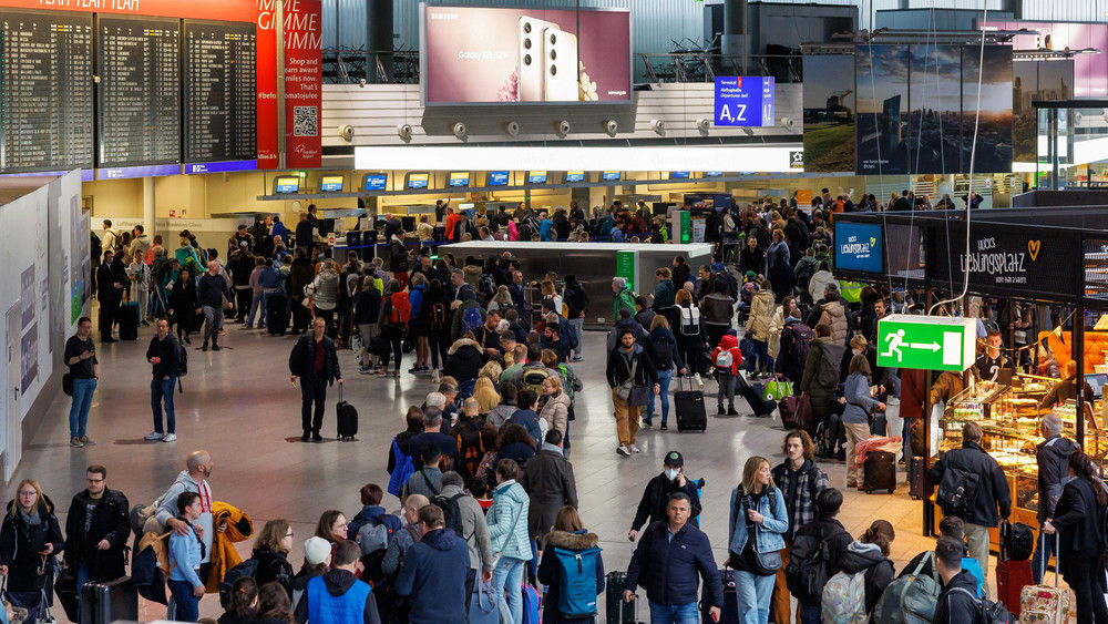 Passagiere stehen im Terminal 1des Frankfurter Flughafens in einer Schlange. Mit dem Beginn der Osterferien beginnt die erste große Reisewelle des Jahres (Archivbild).