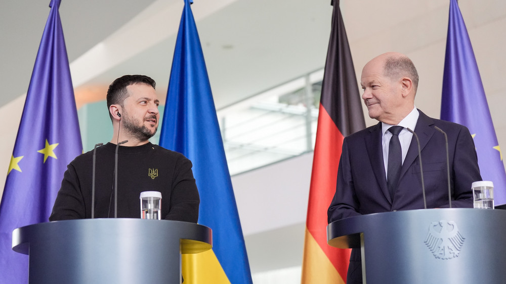 Bundeskanzler Scholz und der ukrainische Präsident Selenskyj stehen am Rednerpult