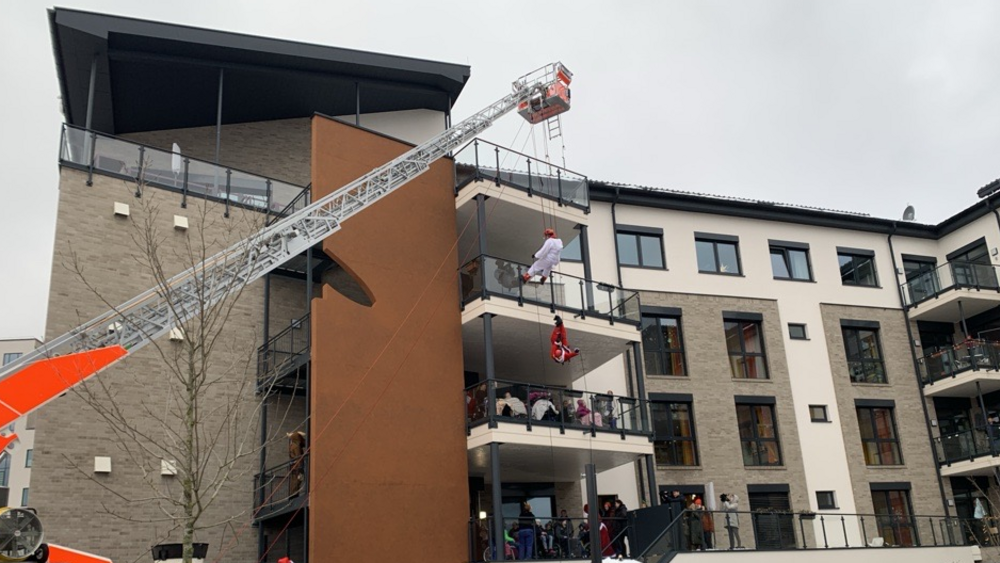 Über Kopf: Die verkleideten Feuerwehrleute seilen sich vom Dach des Zwerg-Nase-Zentrums ab und beschenken die Kinder.