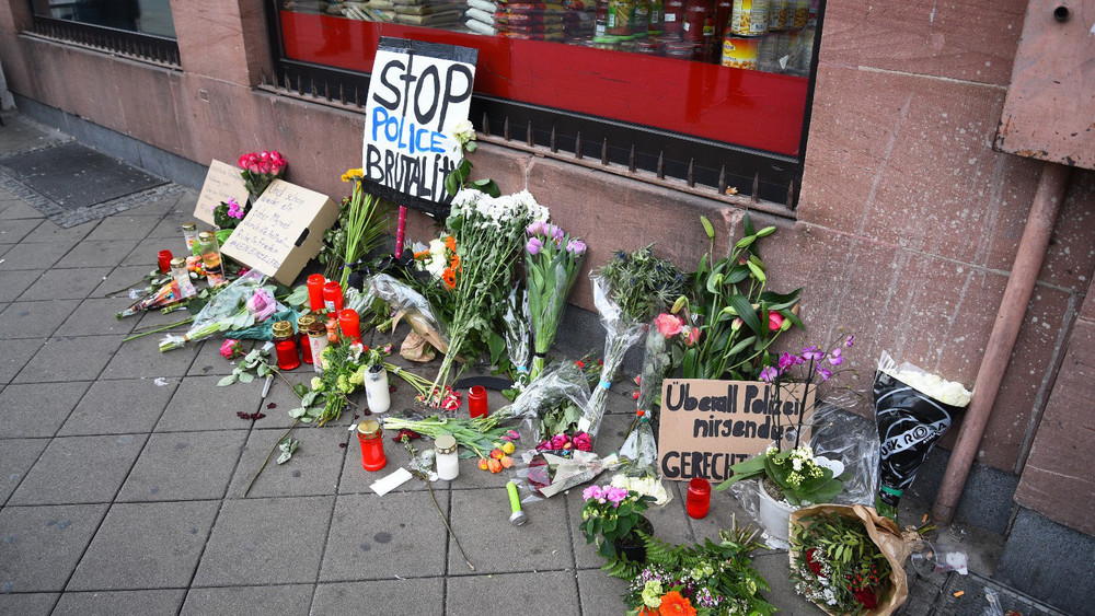 Blumen, Kerzen und Schilder liegen und stehen an dem Ort, an dem am 2. Mai ein Mann bei einer Polizeikontrolle zusammengebrochen ist.
