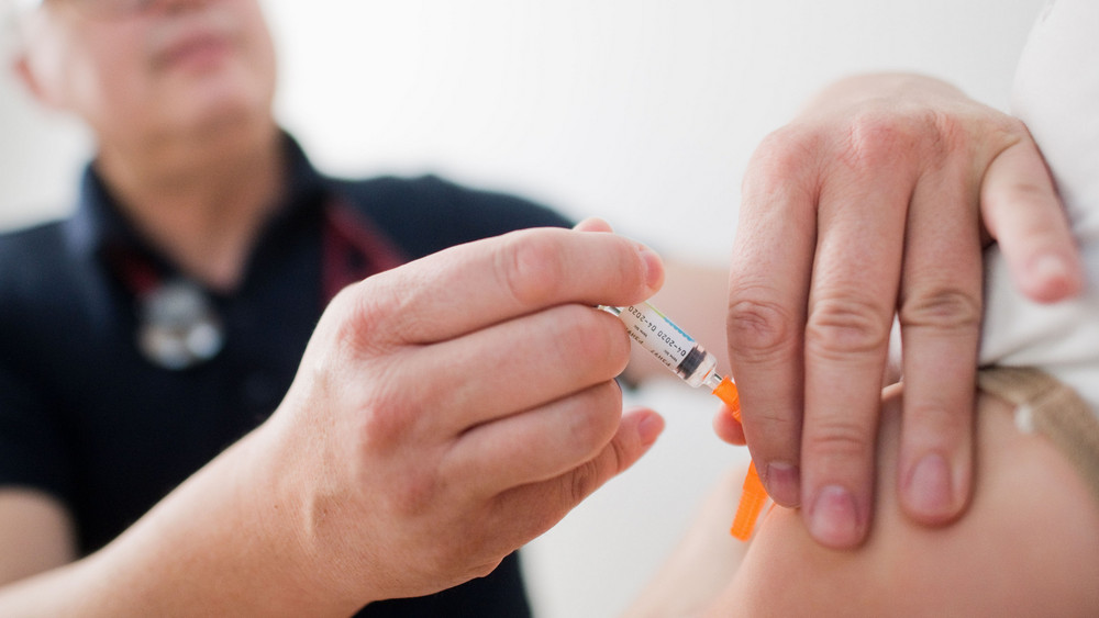 Ein Kinderarzt impft ein Kind mit einem 6-fach-Kombinationsimpfstoff gegen Diphtherie, Tetanus (Wundstarrkrampf), Kinderlähmung (Polio), Keuchhusten (Pertussis), Haemophilus influenzae Typ b (Hib) und Hepatitis B.