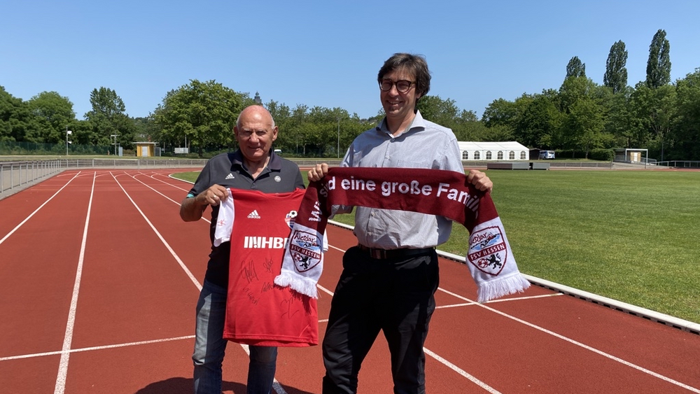 Ralf Koch (Vorsitzender des Sportkreis Lahn-Dill) und Wendelin Müller (stellv. Vorsitzender) zeigen Trikot und Schal ihres Vereins.