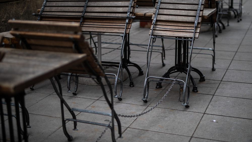 Stühle sind im Außenbereich einer geschlossenen Gastronomischen Einrichtung an Tische gekettet.