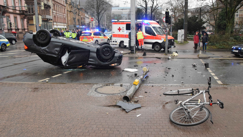 Ein Fahrrad liegt vor dem schwarzen BMW am Boden - es wurde laut Polizei von Trümmerteilen getroffen.