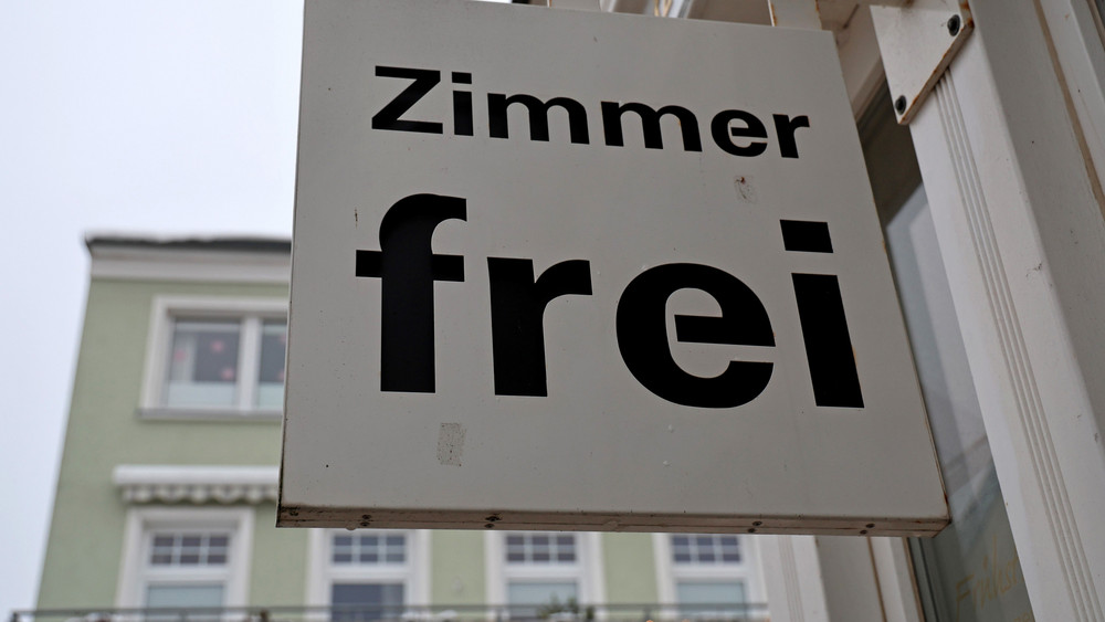 Ein Schild "Zimmer frei" hängt an einem Hotel.