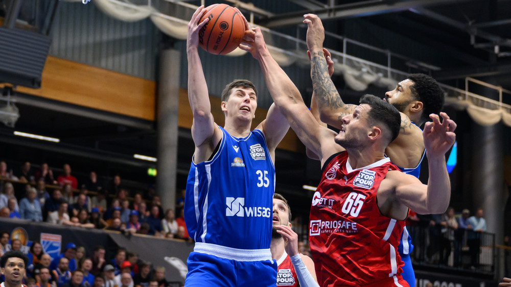 Frankfurts Jacob Knauf (l) und David Muenkat (r) und Bambergs Filip Stanić kämpfen um den Ball.