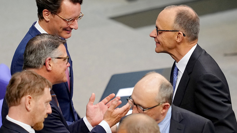 Hessens Ministerpräsident Boris Rhein unterhält sich bei der Kanzler-Wahl im Bundestag mit Friedrich Merz und Hendrik Wüst.