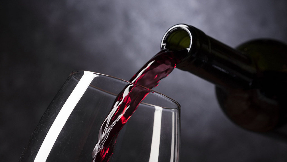 Wein aus Flasche in Glas geschüttet