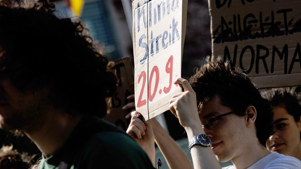 Ein Mitglied von Fridays for Future Deutschland hält vor dem Bundeskanzleramt bei einer Pressekonferenz zum geplanten globalen Klimastreik am 20. September 2024 ein Schild mit der Aufschrift "Klimastreik 20.9.".