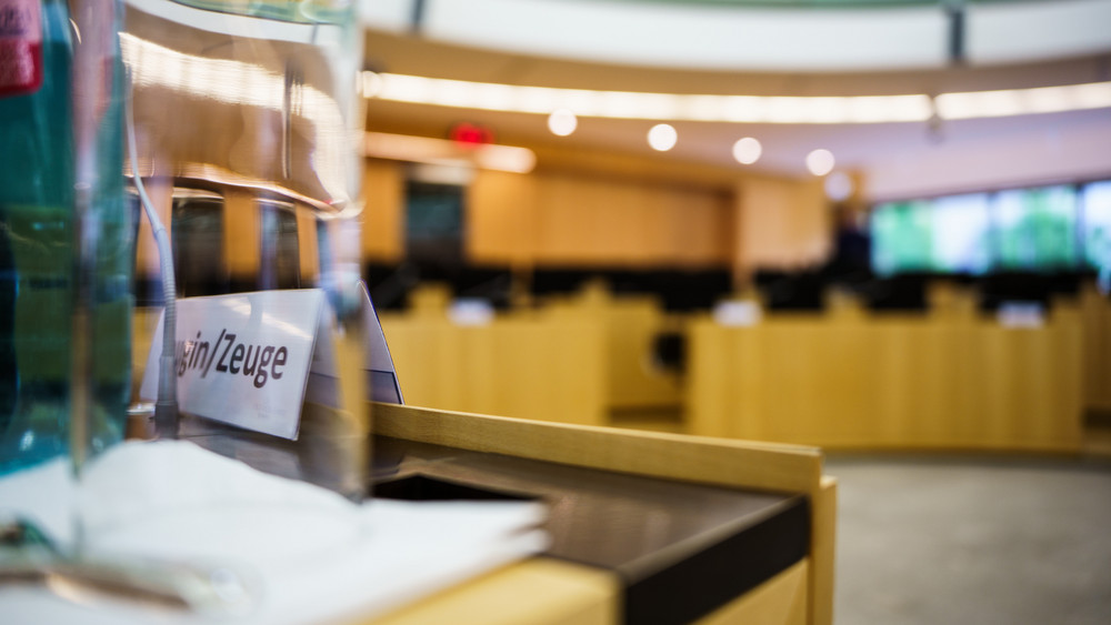 Ein Schild „Zeuge“ steht auf dem Tisch einer Abgeordneten im Landtag. 