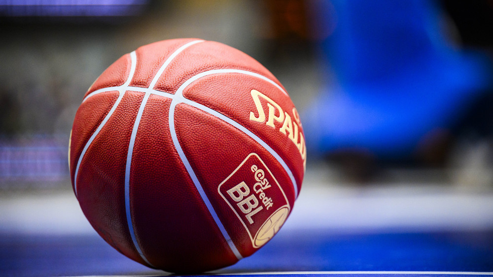 Ein Basketball rollt über das Spielfeld.