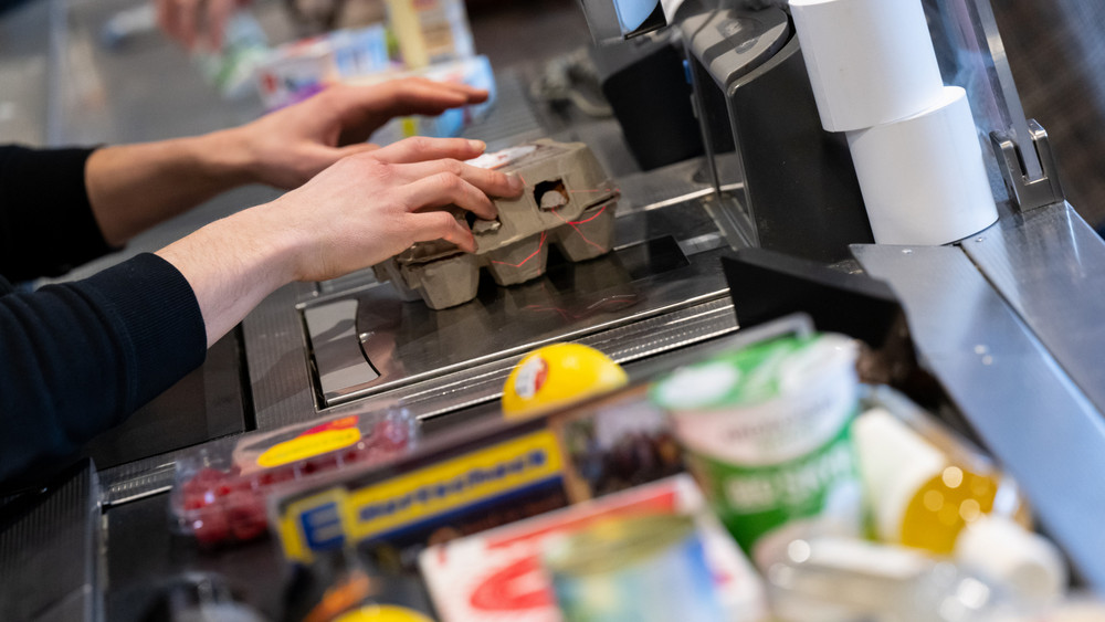 Ein Kassierer scannt in einem Supermarkt an der Kasse die Produkte