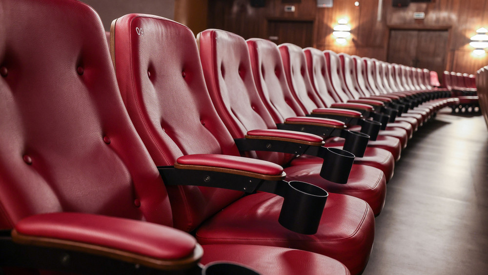 Eine Reihe roter Kinosessel in einem leeren Kino.
