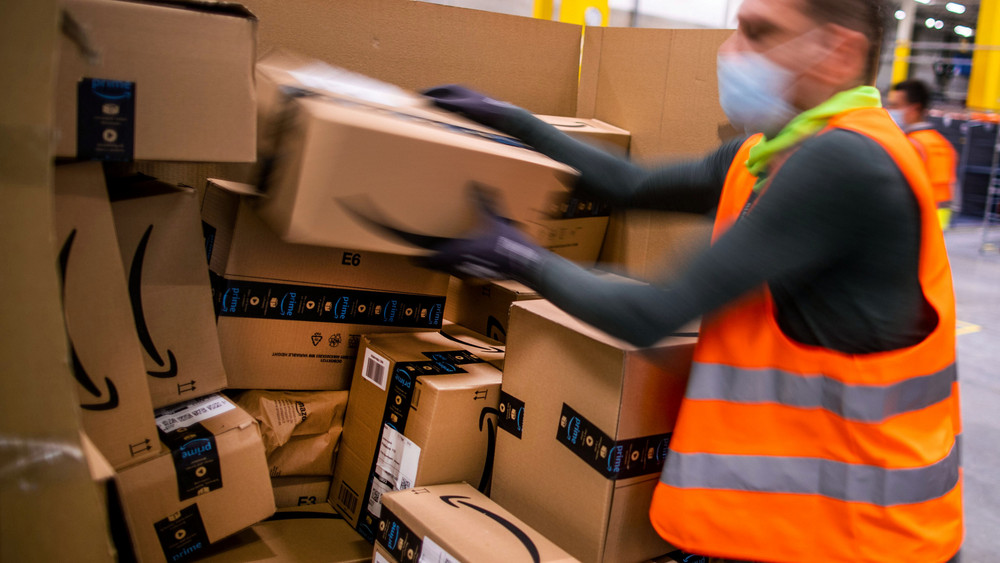 Ein Amazon-Mitarbeiter in einem Verteilzentrum sortiert Pakete