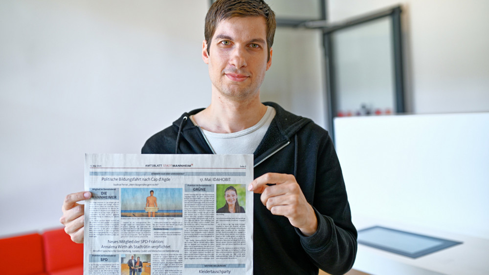 Julien Ferrat mit dem Amtsblatt und seiner Einladung zur FKK-Swinger-Bildungsfahrt ein.