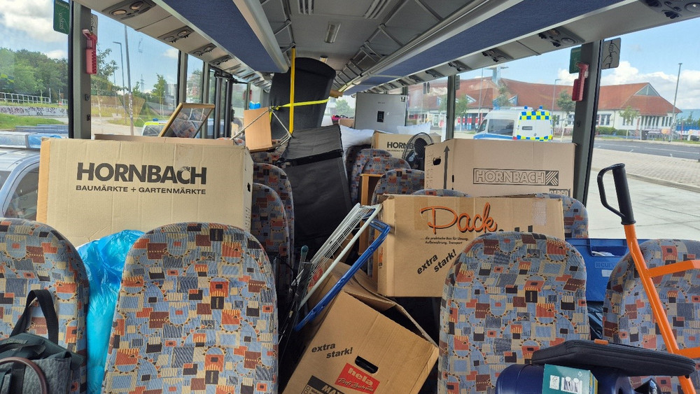 Viele Umzugskartons auf den Sitzen eines Linienbusses