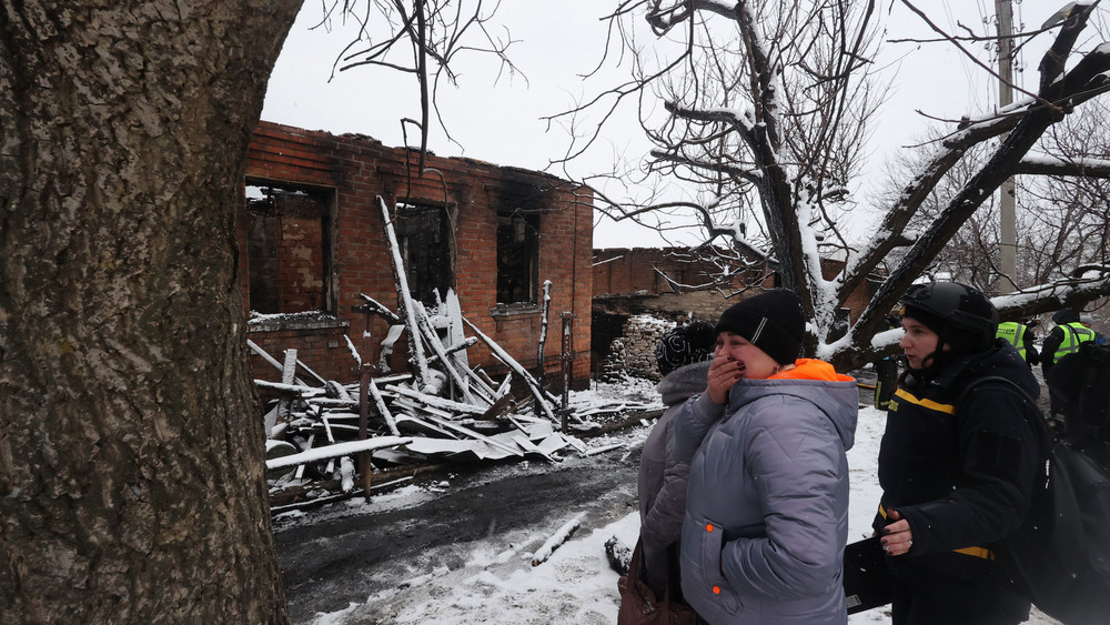 Nach einem russischen Drohnenangriff steht eine Urkainerin vor ihrem zerstörten Haus und weint