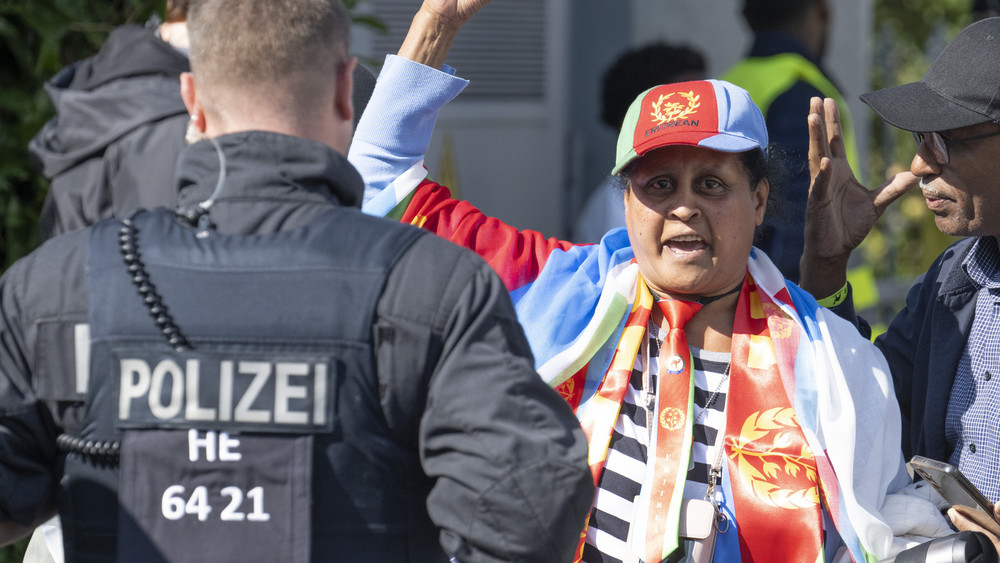 Eine Teilnehmerin am Eritrea-Festival hebt die Faust, ein Polizist beobachtet.